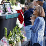 
              A woman stands before a photo of Raleigh shooting victim Susan Karnatz at a makeshift memorial at the Hedingham neighborhood. (Ethan Hyman/The News & Observer via AP)
            