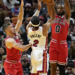 
              Chicago Bulls guards Coby White (0) and Goran Dragic (7) defend against Miami Heat guard Gabe Vincent (2) during the first half of an NBA basketball game Wednesday, Oct. 19, 2022, in Miami. (AP Photo/Marta Lavandier)
            
