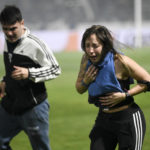 
              Fans of Gimnasia de La Plata choke on tear gas during a local tournament match between Gimnasia de La Plata and Boca Juniors in La Plata, Argentina, Thursday, Oct. 6, 2022. The match was suspended after tear gas thrown by the police outside the stadium wafted inside affecting the players as well as fans who fled to the field to avoid its effects. (AP Photo/Gustavo Garello)
            
