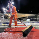 A marshal sweeps the track of surface water after rain delays the start of the Singapore Formula One Grand Prix, at the Marina Bay City Circuit in Singapore, Sunday, Oct. 2, 2022. (AP Photo/Vincent Thian)