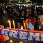 
              Soccer fans chant slogans during a candle light vigil for Arema FC Supporters who became victims of Saturday's soccer match stampede, outside the Youth and Sports Ministry in Jakarta, Indonesia, Sunday, Oct. 2, 2022. Panic and a chaotic run for exits after police fired tear gas at a soccer match between Arema FC and Persebaya in East Java to drive away fans upset with their team's loss left a large number of people dead, most of whom were trampled upon or suffocated. (AP Photo/Dita Alangkara)
            