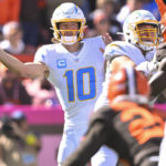 Los Angeles Chargers quarterback Justin Herbert (10) passes as the Los Angeles Chargers defense looks to pressure him during the first half of an NFL football game, Sunday, Oct. 9, 2022, in Cleveland. (AP Photo/David Richard)