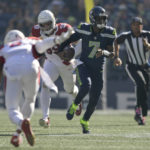 Seattle Seahawks quarterback Geno Smith (7) runs in front of Arizona Cardinals defensive end J.J. Watt (99) during the first half of an NFL football game in Seattle, Sunday, Oct. 16, 2022. (AP Photo/Caean Couto)
