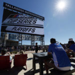 Fans eat and watch the big screen before the NASCAR Cup Series auto race Sunday, Oct. 2, 2022, in Talladega, Ala. (AP Photo/Butch Dill)