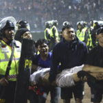 
              Soccer fans carry an injured man following clashes during a soccer match at Kanjuruhan Stadium in Malang, East Java, Indonesia, Saturday, Oct. 1, 2022. Clashes between supporters of two Indonesian soccer teams in East Java province killed over 100 fans and a number of police officers, mostly trampled to death, police said Sunday. (AP Photo/Yudha Prabowo)
            