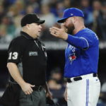 Toronto Blue Jays interim manager John Schneider talks with home plate umpire Todd Tichenor (13) during the fifth inning of Game 2 of the baseball team's AL wild-card playoff series against the Seattle Mariners on Saturday, Oct. 8, 2022, in Toronto. (Nathan Denette/The Canadian Press via AP)