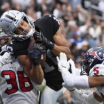 Las Vegas Raiders wide receiver Mack Hollins, center, hauls in a pass for a touchdown between Houston Texans safety Jonathan Owens, left, and safety Jalen Pitre (5) during the first half of an NFL football game Sunday, Oct. 23, 2022, in Las Vegas. (AP Photo/David Becker)