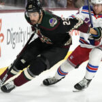 Arizona Coyotes center Jack McBain (22) tries to keep the puck away from New York Rangers defenseman Adam Fox (23) during the first period of an NHL hockey game at Mullett Arena in Tempe, Ariz., Sunday, Oct. 30, 2022. (AP Photo/Ross D. Franklin)