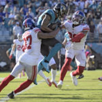 Jacksonville Jaguars wide receiver Christian Kirk (13) is stopped by New York Giants cornerback Fabian Moreau (37) and safety Julian Love (20) during the second half of an NFL football game Sunday, Oct. 23, 2022, in Jacksonville, Fla. (AP Photo/Phelan M. Ebenhack)
