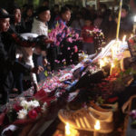 
              People throw flowers during a candle light vigil for the victims of Saturday's soccer riots outside Kanjuruhan Stadium where it broke out, in Malang, East Java, Indonesia, Sunday, Oct. 2, 2022. Police firing tear gas after an Indonesian soccer match in an attempt to stop violence triggered a disastrous crush of fans making a panicked, chaotic run for the exits, leaving a large number of people dead, most of them trampled upon or suffocated. (AP Photo/Trisnadi)
            