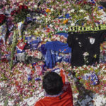 
              A man throws flowers outside Kanjuruhan Stadium where a soccer stampede killed more than 100 people on Saturday, in Malang, East Java, Indonesia, Tuesday, Oct. 4, 2022. An Indonesian police chief and nine elite officers were removed from their posts Monday and 18 others were being investigated for responsibility in the firing of tear gas inside a soccer stadium that set off a stampede, officials said. (AP Photo/Dicky Bisinglasi)
            