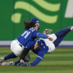 
              Toronto Blue Jays shortstop Bo Bichette (11) and center fielder George Springer (4) collide while to trying to catch a three-RBI double off the bat of Seattle Mariners shortstop J.P. Crawford during  the eighth inning of Game 2 of a baseball AL wild-card playoff series, Saturday, Oct. 8, 2022, in Toronto. (Frank Gunn/The Canadian Press via AP)
            