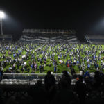 
              Fans of Gimnasia de La Plata take to the pitch after tear gas flooded the stadium during a local tournament soccer match between Gimnasia de La Plata and Boca Juniors in La Plata, Argentina, Thursday, Oct. 6, 2022. The match was suspended after tear gas thrown by the police outside the stadium wafted inside affecting the players as well as fans who fled to the field to avoid its effects. (AP Photo/Gustavo Garello)
            