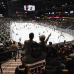 Fans watch players as they warm up prior to the Arizona Coyotes NHL home opening hockey game against the Winnipeg Jets at the 5,000 seat Mullett Arena in Tempe, Ariz., Friday, Oct. 28, 2022. (AP Photo/Ross D. Franklin)