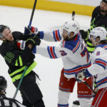 Dallas Stars center Ty Dellandrea (10) scuffles with New York Rangers defensemen K'Andre Miller (79) and Jacob Trouba (8) during the second period of an NHL hockey game in Dallas, Saturday, Oct. 29, 2022. (AP Photo/Michael Ainsworth)