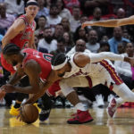 Chicago Bulls guard Coby White (0) and Miami Heat guard Gabe Vincent (2) go after a loose ball during the first half of an NBA game Wednesday, Oct. 19, 2022, in Miami. (AP Photo/Marta Lavandier)