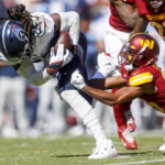 Tennessee Titans running back Derrick Henry (22) carries the ball as Washington Commanders cornerback Kendall Fuller (29) tries to bring him down during the first half of an NFL football game Sunday, Oct. 9, 2022 in Landover, Va. (Shaban Athuman/Richmond Times-Dispatch via AP)