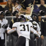 Wake Forest's Sam Hartman, top, tries to leap over Army's Leo Lowin (31) during the second half of an NCAA college football game in Winston-Salem, N.C., Saturday, Oct. 8, 2022. (AP Photo/Chuck Burton)