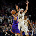 Phoenix Suns guard Devin Booker passes under pressure from New Orleans Pelicans forward Larry Nance Jr. (22) during the first half of an NBA basketball game, Friday, Oct. 28, 2022, in Phoenix. (AP Photo/Matt York)