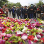 
              Flowers are sprinkled as supporters of local soccer club Arema FC pray, outside Kanjuruhan Stadium where a riots broke out on Saturday night in Malang, East Java, Indonesia, Sunday, Oct. 2, 2022. Panic at the soccer match between Arema FC and Persebaya of Surabaya city left over 150 people dead, most of whom were trampled to death after police fired tear gas to dispel the riots. (AP Photo/Trisnadi)
            
