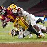 Southern California wide receiver Jordan Addison, left, is tackled by Arizona State defensive back Khoury Bethley, top, and defensive back Timarcus Davis during the second half of an NCAA college football game Saturday, Oct. 1, 2022, in Los Angeles. (AP Photo/Mark J. Terrill)