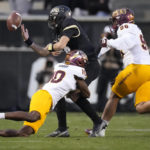 Colorado quarterback J.T. Shrout, back left, fumbles the ball as he is hit by Arizona State defensive back Ed Woods, front left, while Arizona State defensive lineman Anthonie Cooper, right, trails the play in the first half of an NCAA college football game Saturday, Oct. 29, 2022, in Boulder, Colo. (AP Photo/David Zalubowski)