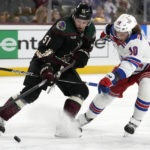 Arizona Coyotes defenseman Troy Stecher (51) tries to control the puck as he is hit by New York Rangers left wing Artemi Panarin (10) during the second period of an NHL hockey game at Mullett Arena in Tempe, Ariz., Sunday, Oct. 30, 2022. (AP Photo/Ross D. Franklin)