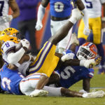 LSU wide receiver Malik Nabers (8) is brought down by Florida cornerback Jason Marshall Jr., bottom left, and safety Kamari Wilson (5) during the second half of an NCAA college football game, Saturday, Oct. 15, 2022, in Gainesville, Fla. (AP Photo/John Raoux)