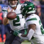 
              New York Jets quarterback Zach Wilson (2) tosses the ball to New York Jets running back Breece Hall (20) during the first half of an NFL football game between the Denver Broncos and the New York Jets, Sunday, Oct. 23, 2022, in Denver. (AP Photo/Matt York)
            