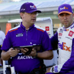 
              Driver Denny Hamlin, right, stands on pit road during NASCAR Cup Series practice at Homestead-Miami Speedway, Saturday, Oct. 22, 2022, in Homestead, Fla. (AP Photo/Lynne Sladky)
            