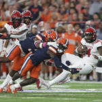 Syracuse defensive back Garrett Williams (8) and linebacker Mikel Jones (3) tackle North Carolina State quarterback Jack Chambers (14) during the first half of an NCAA college football game Saturday, Oct. 15, 2022, in Syracuse, N.Y. (AP Photo/Joshua Bessex)