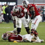 North Carolina State's Chandler Zavala (64) and Derrick Eason (53) check on quarterback Devin Leary (13) following a hit by Florida State's Joshua Farmer during the second half of an NCAA college football game in Raleigh, N.C., Saturday, Oct. 8, 2022. (AP Photo/Karl B DeBlaker)