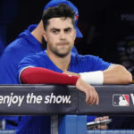 Toronto Blue Jays' Whit Merrifield watches from the dugout during the fifth inning of Game 2 of a baseball AL wild-card playoff series Saturday, Oct. 8, 2022, in Toronto. Merrifield was hit by a Seattle Mariners pitch in the inning. (Frank Gunn/The Canadian Press via AP)