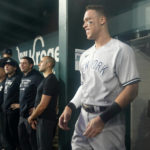 New York Yankees' Aaron Judge smiles in the dugout after hitting a solo home run, his 62nd of the season, during the first inning in the second baseball game of a doubleheader against the Texas Rangers in Arlington, Texas, Tuesday, Oct. 4, 2022. With the home run, Judge set the AL record for home runs in a season, passing Roger Maris. (AP Photo/LM Otero)
