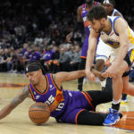 Phoenix Suns guard Damion Lee and Golden State Warriors guard Ty Jerome (10) battle for a loose ball during the second half of an NBA basketball game, Tuesday, Oct. 25, 2022, in Phoenix. Phoenix won 134-105. (AP Photo/Rick Scuteri)