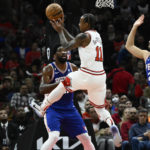 
              Chicago Bulls forward DeMar DeRozan (11) passes the ball away from Philadelphia 76ers guard De'Anthony Melton (8), center Joel Embiid (21) and forward Georges Niang (20) during the first half of an NBA basketball game, Saturday, Oct. 29, 2022, in Chicago. (AP Photo/Matt Marton)
            