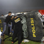 
              Officers examine a damaged police vehicle following a clash between supporters of two Indonesian soccer teams at Kanjuruhan Stadium in Malang, East Java, Indonesia, Saturday, Oct. 1, 2022. Panic following police actions left over 100 dead, mostly trampled to death, police said Sunday. (AP Photo/Yudha Prabowo)
            