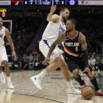 
              Portland Trail Blazers' Damian Lillard drives around Los Angeles Clippers' Ivica Zubac with Nicolas Batum (33) behind during the first half of an NBA preseason basketball game, Monday, Oct. 3, 2022, in Seattle. (AP Photo/ John Froschauer)
            
