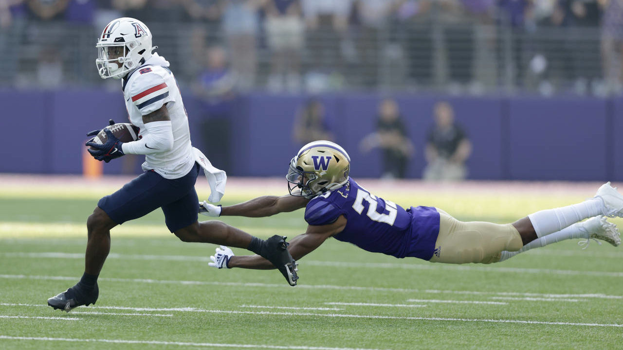 Arizona wide receiver Jacob Cowing catches a pass with Washington cornerback Mishael Powell diving ...