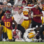 Southern California wide receiver Kyron Hudson (10) gets up after catching a pass as members of his team celebrate while Arizona State defensive back Timarcus Davis (7) lays on the ground during the first half of an NCAA college football game Saturday, Oct. 1, 2022, in Los Angeles. (AP Photo/Mark J. Terrill)