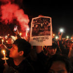 
              Soccer fans light a flare during a candle light vigil for the victims of Saturday's stampede, in Yogyakarta, Indonesia, Tuesday, Oct. 4, 2022. Police firing tear gas inside a stadium in East Java on Saturday in an attempt to stop violence after an Indonesian soccer match triggered a disastrous crush of fans making a panicked, chaotic run for the exits, leaving at a number of people dead, most of them trampled upon or suffocated. Writing on the poster reads "Investigate thoroughly". (AP Photo/Slamet Riyadi)
            