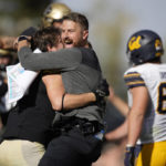 
              Colorado interim head coach Mike Sanford, center, hugs linebacker Thomas Notarianni, left, as California offensive lineman Brian Driscoll, right, walks off the field after overtime in an NCAA college football game at Folsom Field, Saturday, Oct. 15, 2022, in Boulder, Colo. (AP Photo/David Zalubowski)
            