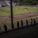 
              Students do their gymnastics homework on the bleachers of the Pedro Marrero stadium while they watch as a group of teenagers train soccer in Havana, Cuba, Wednesday, Sept. 14, 2022. An initial group of 16 coaches were recently trained by international FIFA officials with the aim to create Cuba's next generation of professional soccer players on an island long known for birthing baseball and boxing superstars. The aim is for Cuba to qualify for the World Cup in the next six to eight years. (AP Photo/Ramon Espinosa)
            
