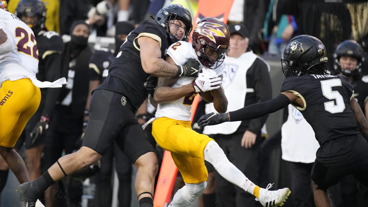 Arizona State wide receiver Elijhah Badger, center, is tackled by Colorado linebacker Quinn Perry, ...