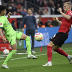 Leverkusen's Mitchel Bakker, right and Wolfsburg's Kevin Paredes fight for the ball, during the German Bundesliga soccer match between Bayer 04 Leverkusen and VfL Wolfsburg, at the BayArena, in Leverkusen, Germany, Saturday, Oct. 22, 2022. (Federico Gambarini/dpa via AP)