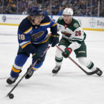 St. Louis Blues' Robert Thomas (18) handles the puck as Minnesota Wild's Connor Dewar (26) defends during the first period of a preseason NHL hockey game Tuesday, Oct. 4, 2022, in St. Louis. (AP Photo/Jeff Roberson)