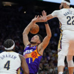 Phoenix Suns guard Devin Booker (1) is fouled by New Orleans Pelicans guard Devonte' Graham (4) as forward Larry Nance Jr. (22) defends during the second half of an NBA basketball game, Friday, Oct. 28, 2022, in Phoenix. (AP Photo/Matt York)
