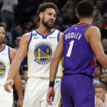 Golden State Warriors guard Klay Thompson (11) and Phoenix Suns guard Devin Booker (1) talk to each other during the second half of an NBA basketball game, Tuesday, Oct. 25, 2022, in Phoenix. Phoenix won 134-105. (AP Photo/Rick Scuteri)