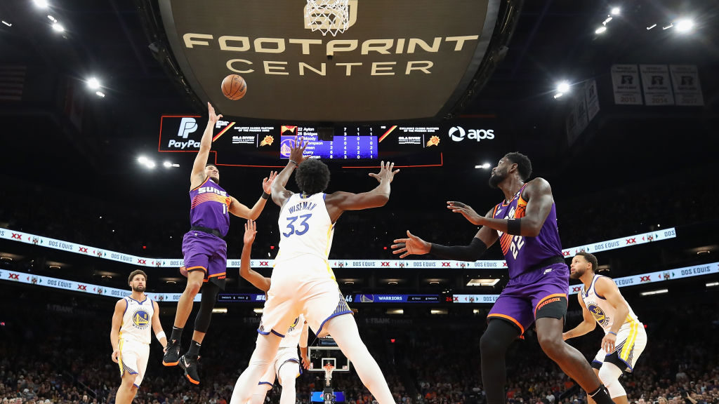 Devin Booker #1 of the Phoenix Suns puts up a shot over James Wiseman #33 of the Golden State Warri...