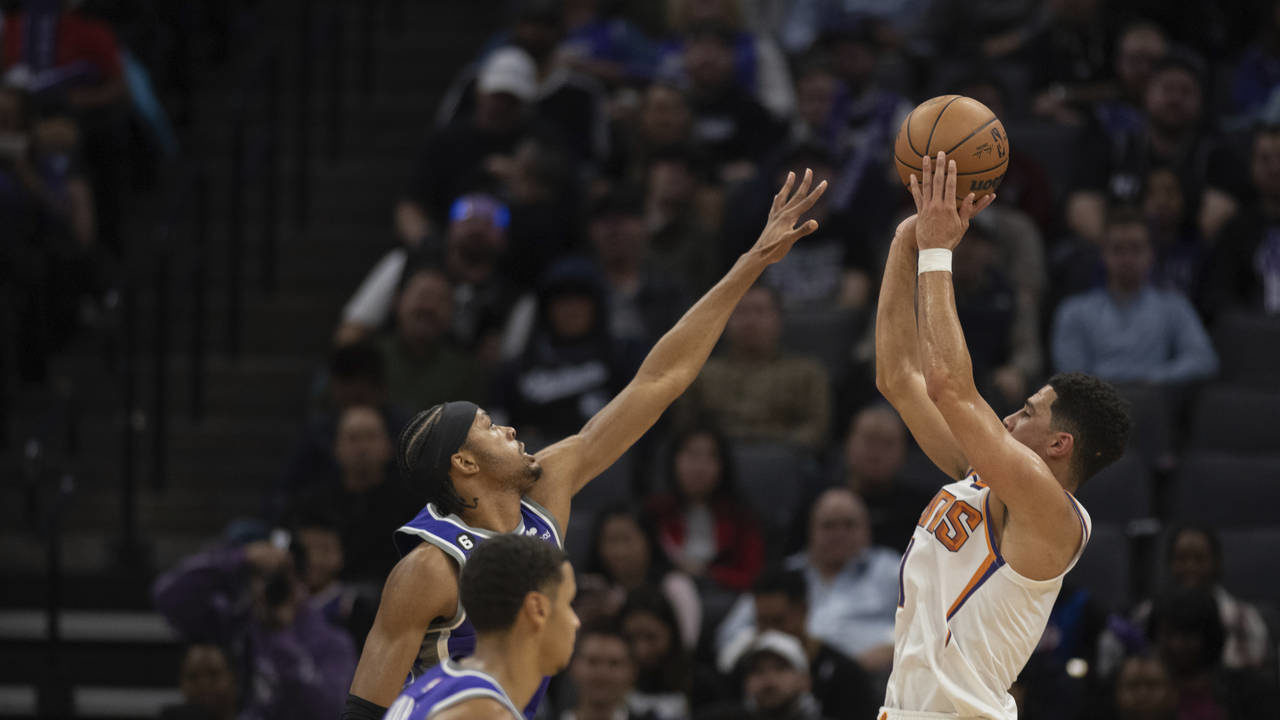 Phoenix Suns guard Devin Booker, right, looks to score a basket against Sacramento Kings forward KZ...